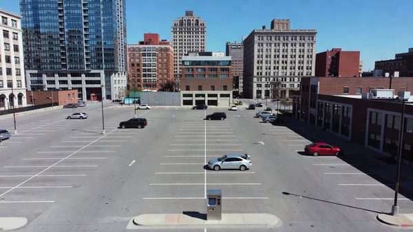 An open urban parking lot entrance without a gate arm, with downtown Cincinnati buildings visible